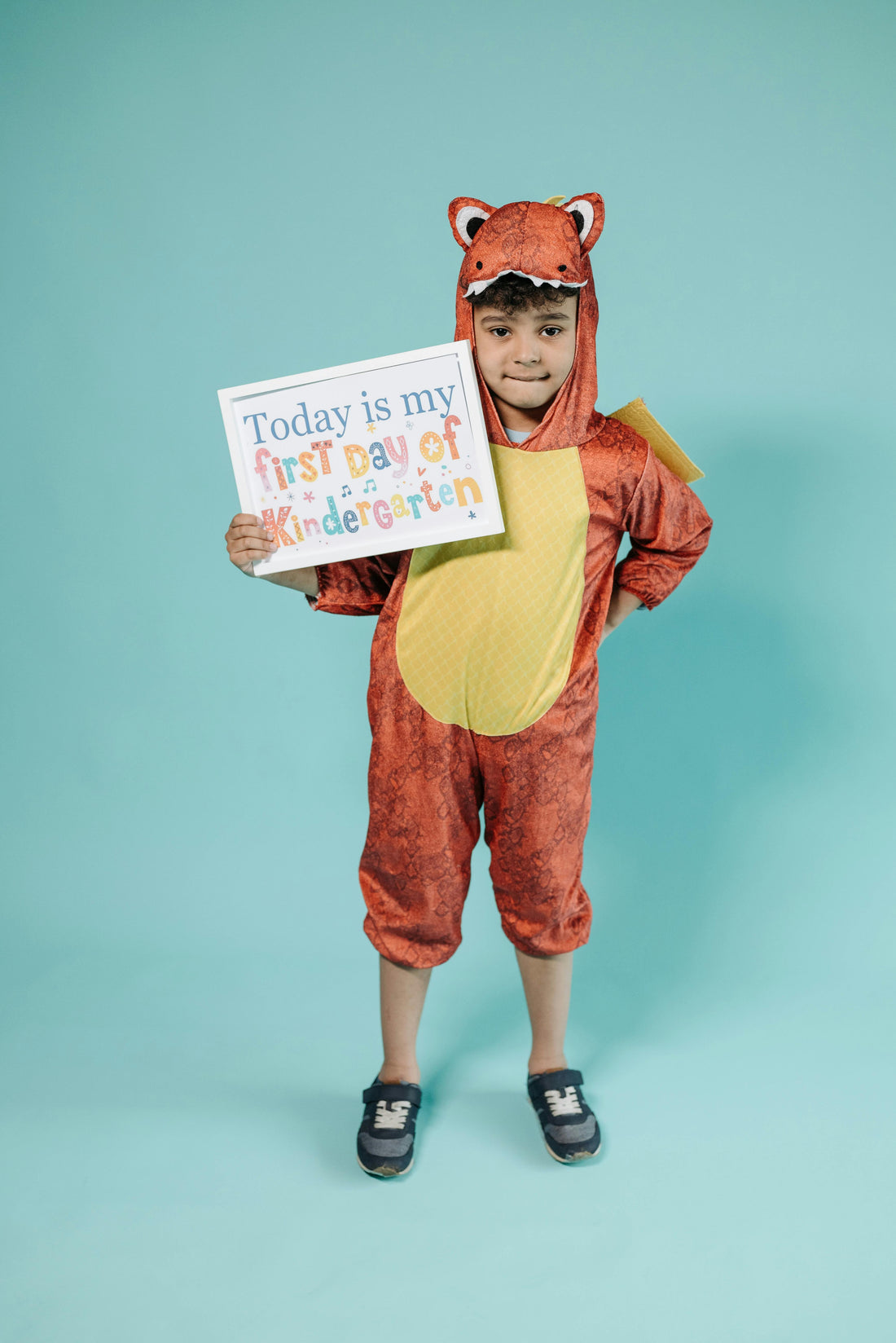 Young child holding sign that says first day of kindergarden